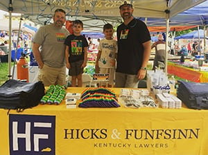 Photo of attorneys of Hicks & Funfsinn standing behind firm table at the Lexington Pride Festival